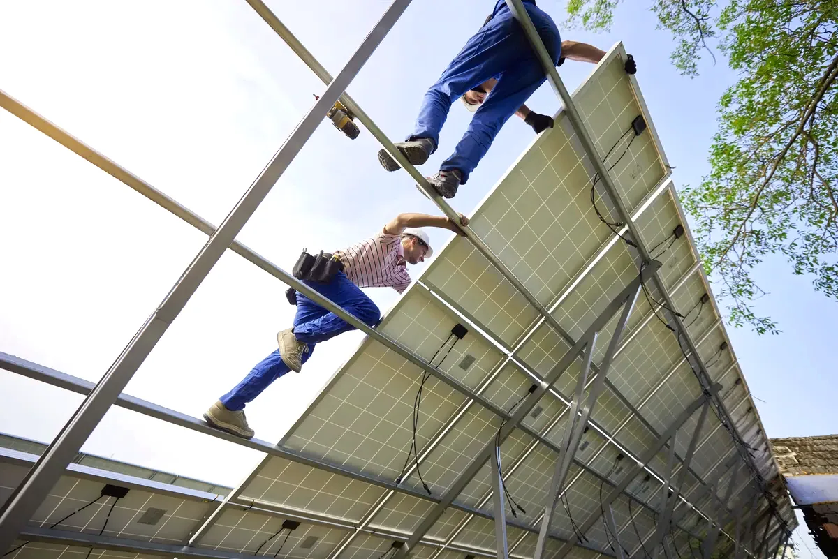 Instaladores sobre la estructura metálica de soporte de unos paneles solares durante una instalación en Badalona