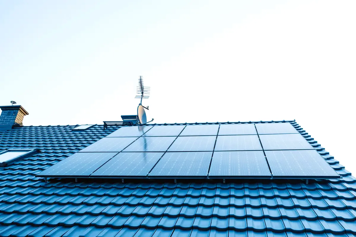 Paneles solares sobre un tejado de tejas bajo un cielo despejado, sol típico de Badalona para producir energía